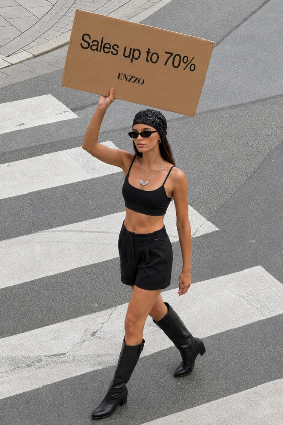 Girl in black top and shorts holding a Placard about sitewide sales